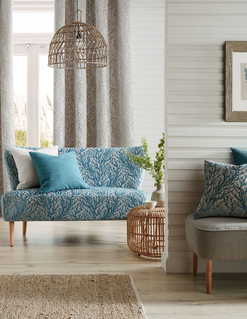 A coastal inspired room with blue coral sofa and cosy grey curtains. 