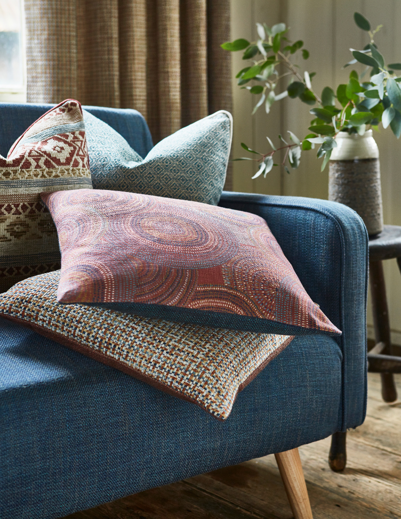 A rich blue sofa with an eclectic mix of patterned cushions. 