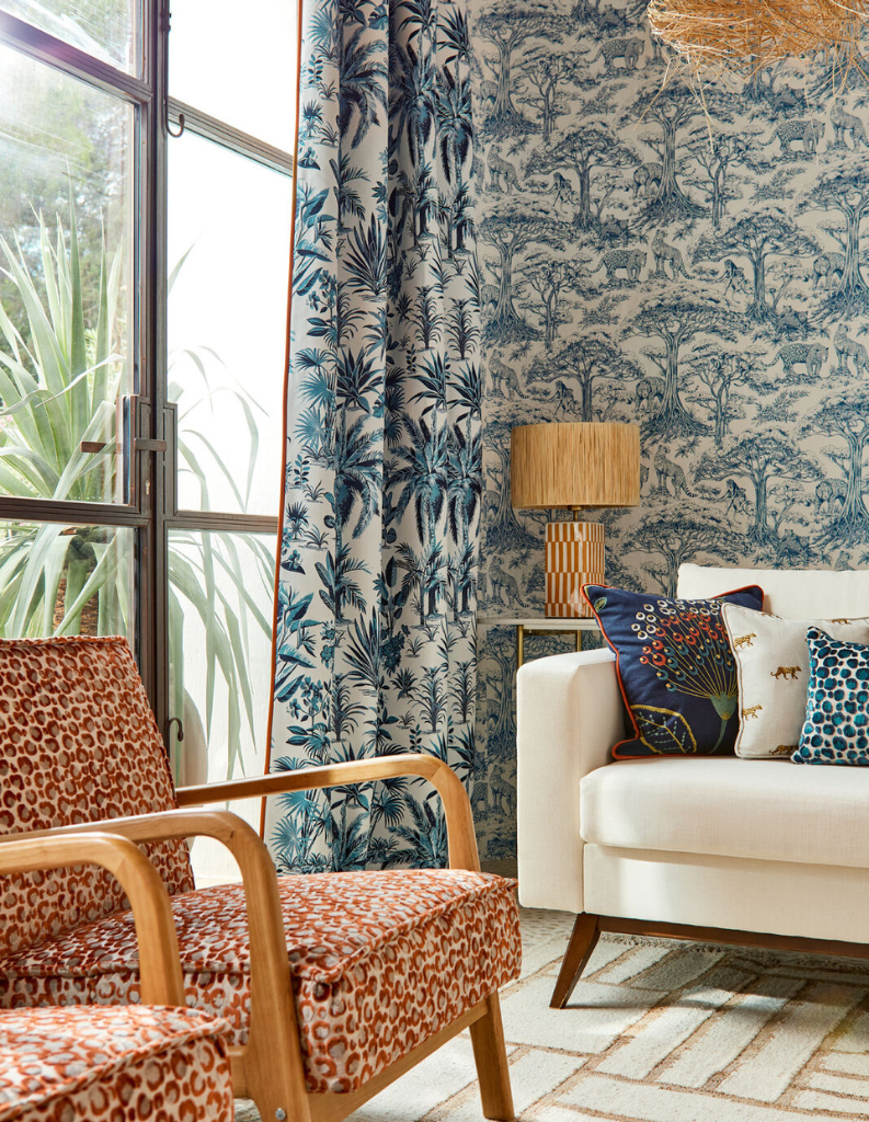 Mixed patterns in a living room featuring blue curtains, walls and red chairs. 