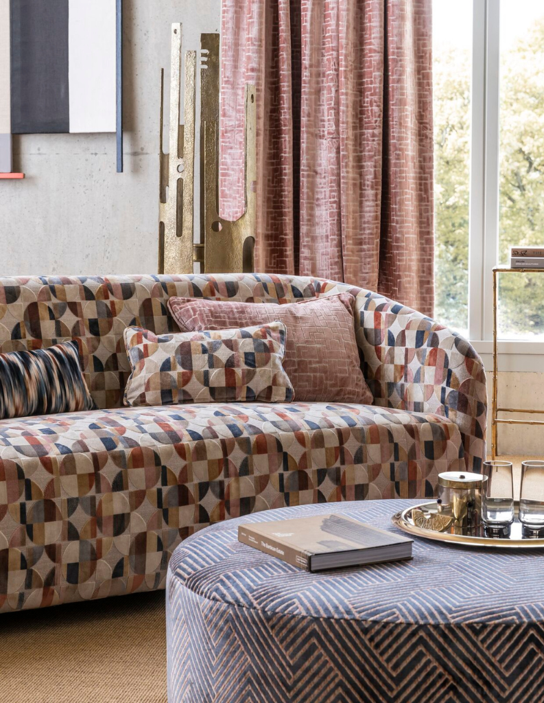 Pink curtains with a colourful patterned sofa.