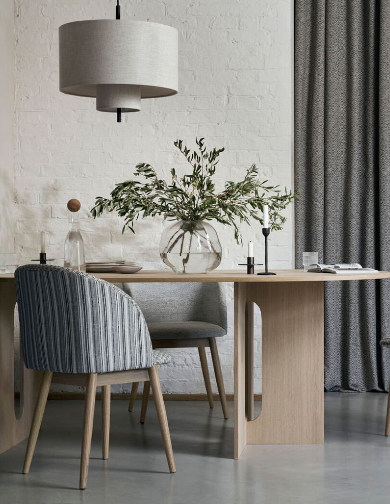 An organic modern dining area featuring grey curtains and a futuristic table. 