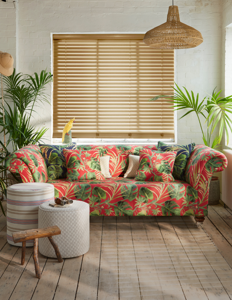 Smart wooden blinds in a tropical living room with red patterned sofa and matching cushions.