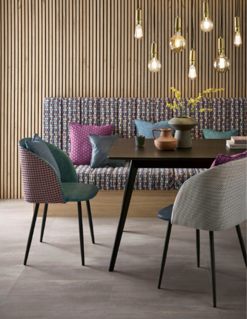 An eclectic dining area featuring bold coloured cushions, fun lighting and modern chairs.