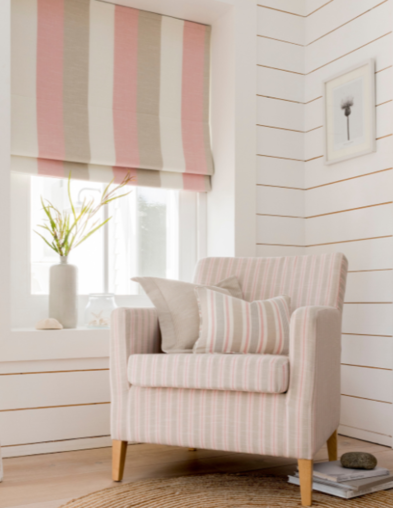 An image showcasing wide striped Roman blinds alongside striped cushions in a coastal style room.