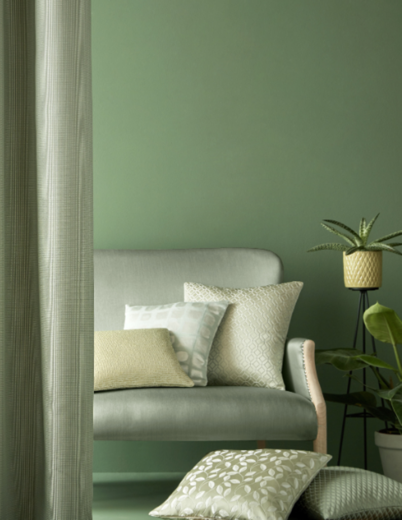 A mono green room featuring different shades of green in curtains, cushions and wall paint.