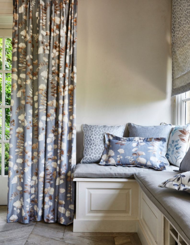 A cosy sitting area with patterned blue cushions and curtain. 