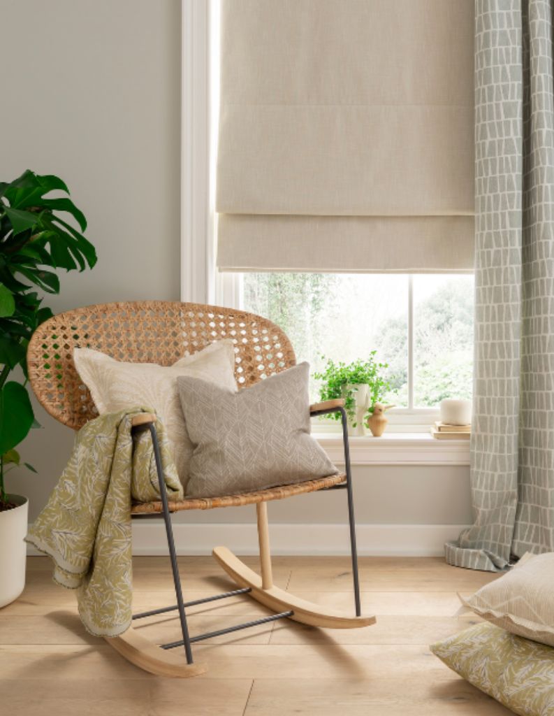  A cosy reading area featuring calming colours, a neutral Roman blind and patterned grey curtains. 