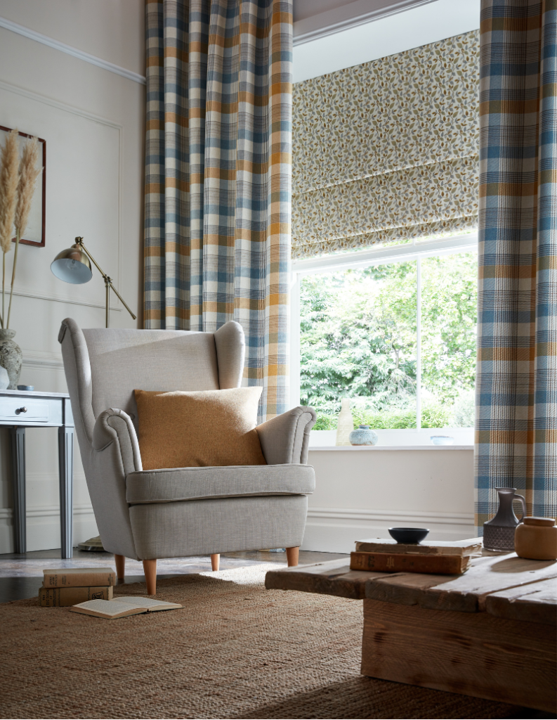 A cosy cottage inspired living room with checked curtains and floral Roman blinds.