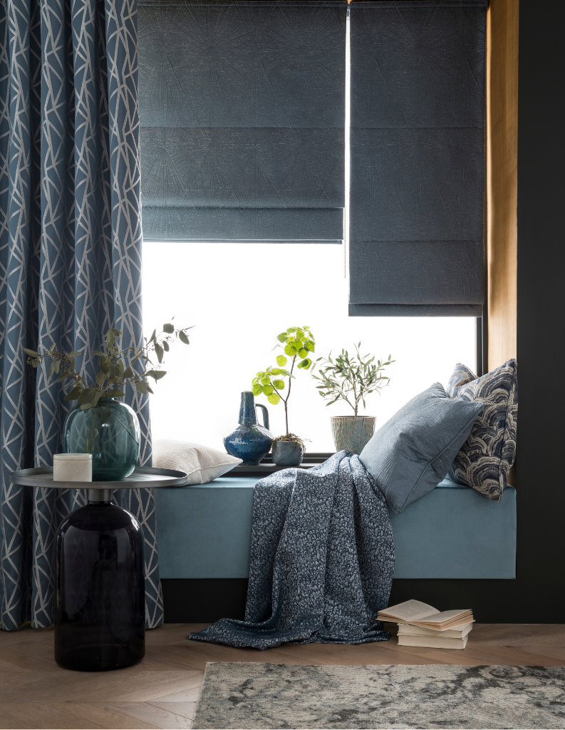 A blue sitting area with patterned curtains and blue Roman blinds.