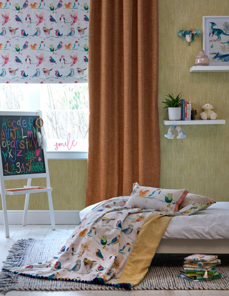 A playful kids room with orange curtains, bird pattern Roman blinds and plenty of toys.