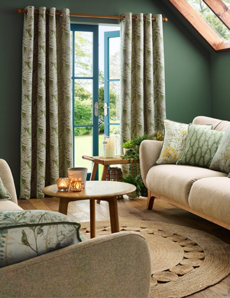 A forest green sitting room with chunky furniture and curtains.