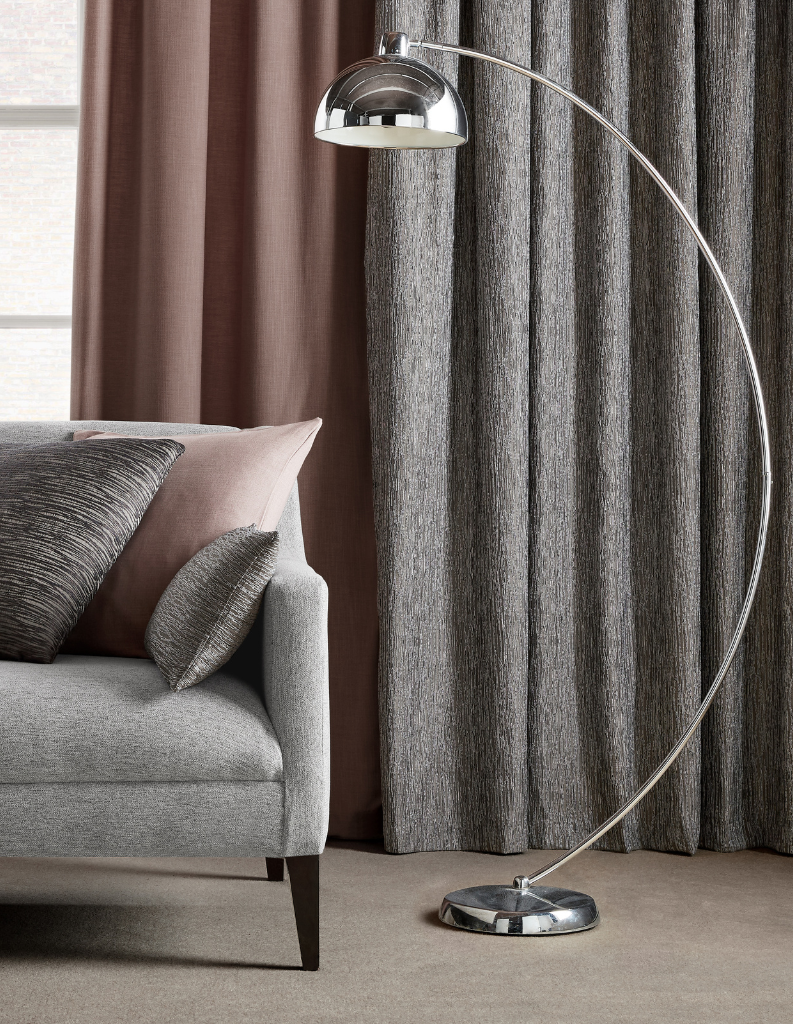 Rich grey curtains behind a chrome lamp.