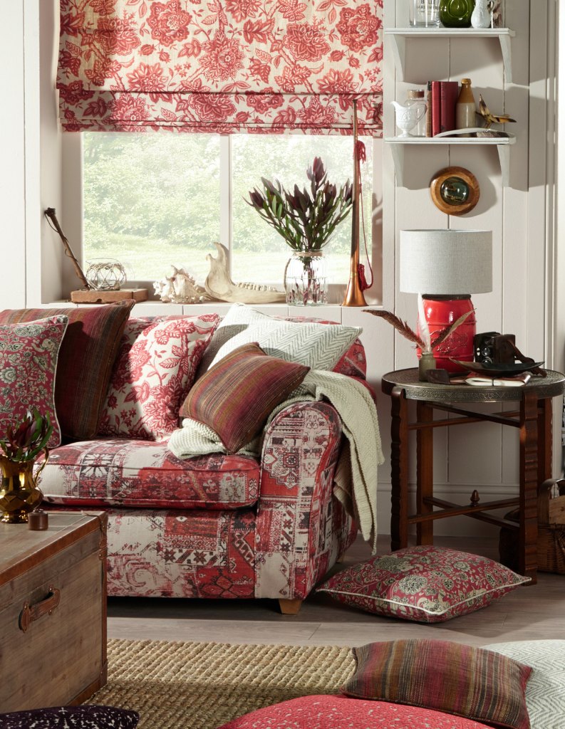 An autumnal living room with red patterns and a Roman blinds at the window. 