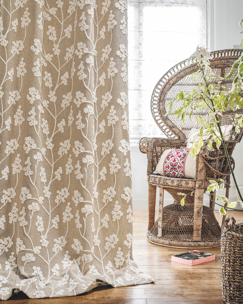 a 70s inspired living room with floral curtains and wicker chair.