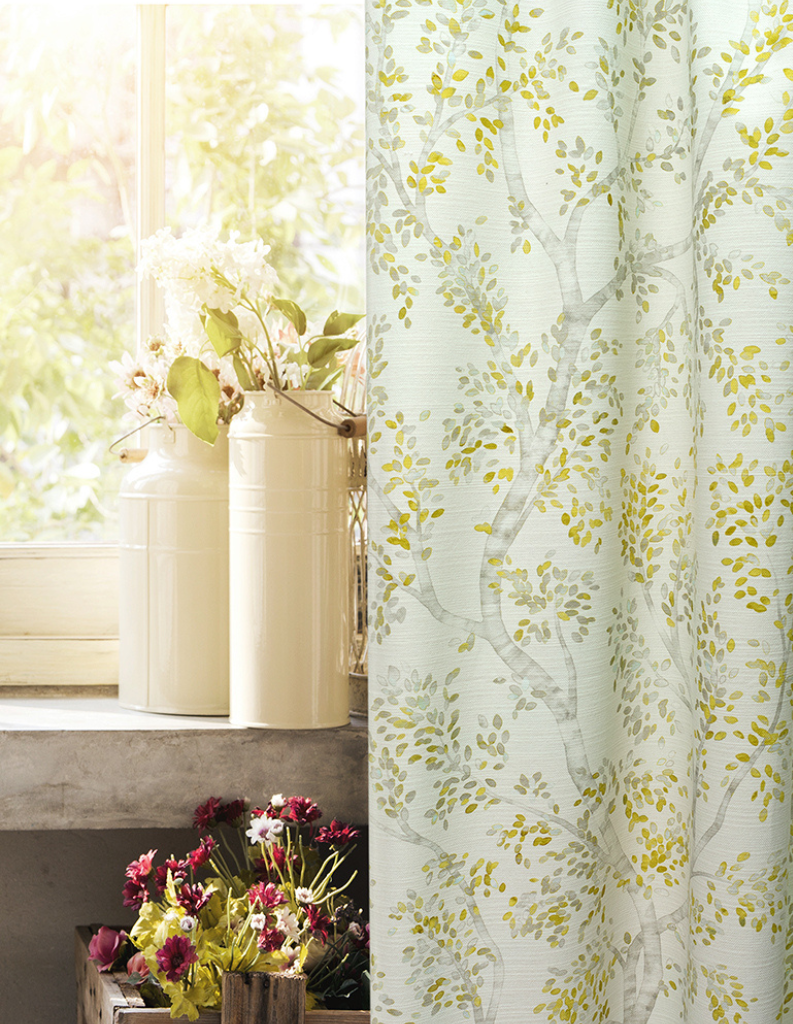 A sunny window featuring a yellow patterned curtain and potted plants