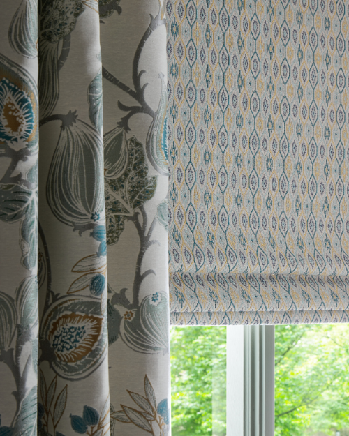 A layered window featuring curtains and a Roman blind.